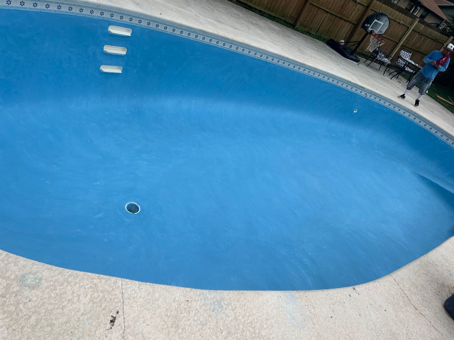 A large blue swimming pool with people standing around it.