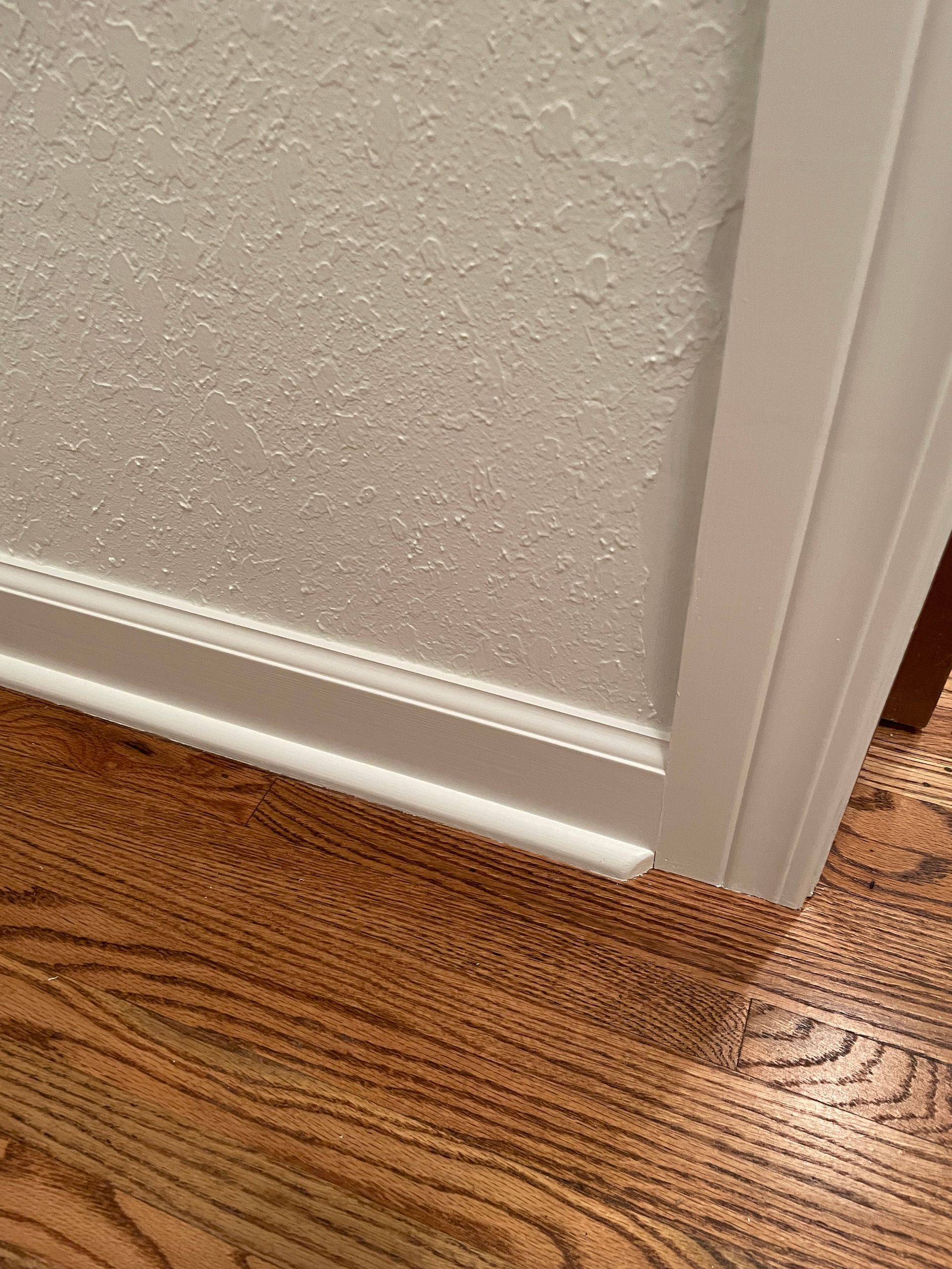 A close up of a door with a white trim and a wooden floor.