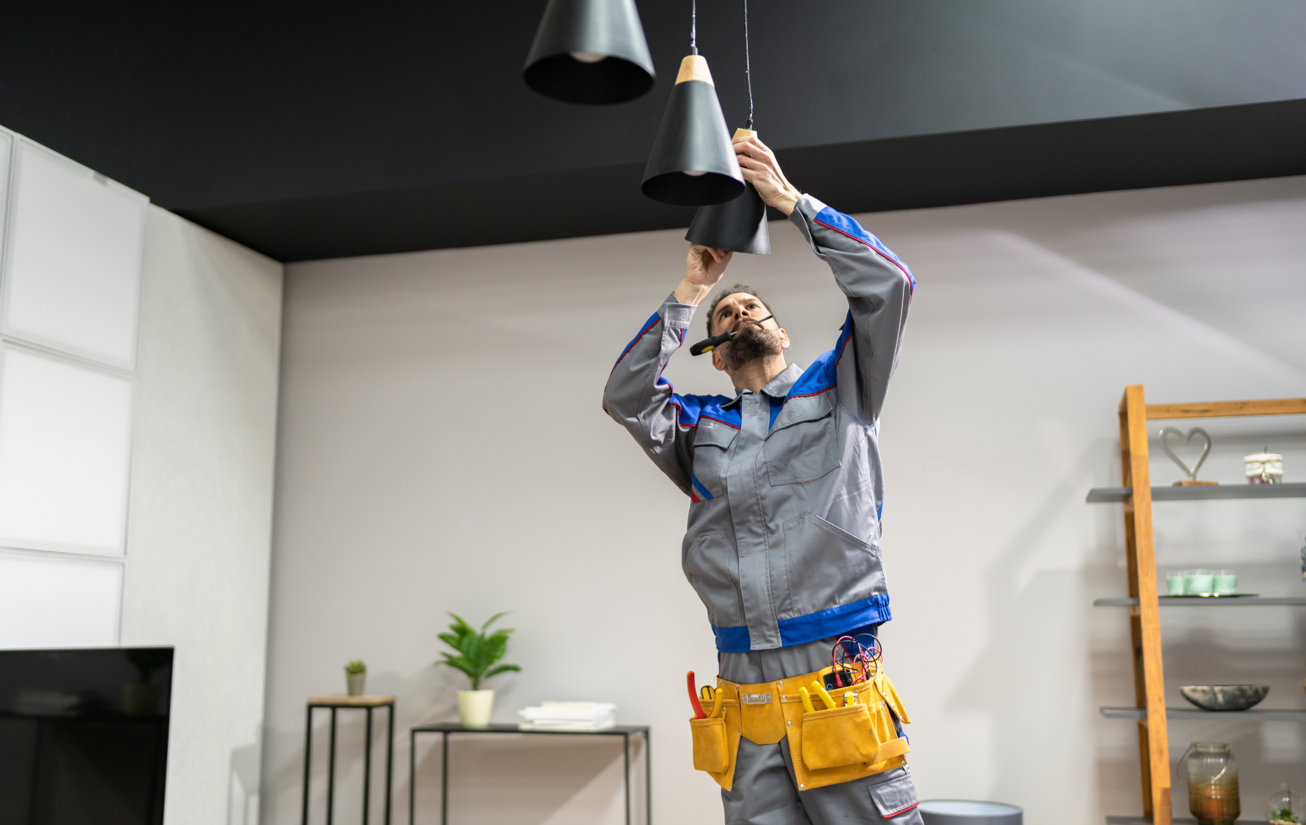 A man is installing a light fixture in a living room.