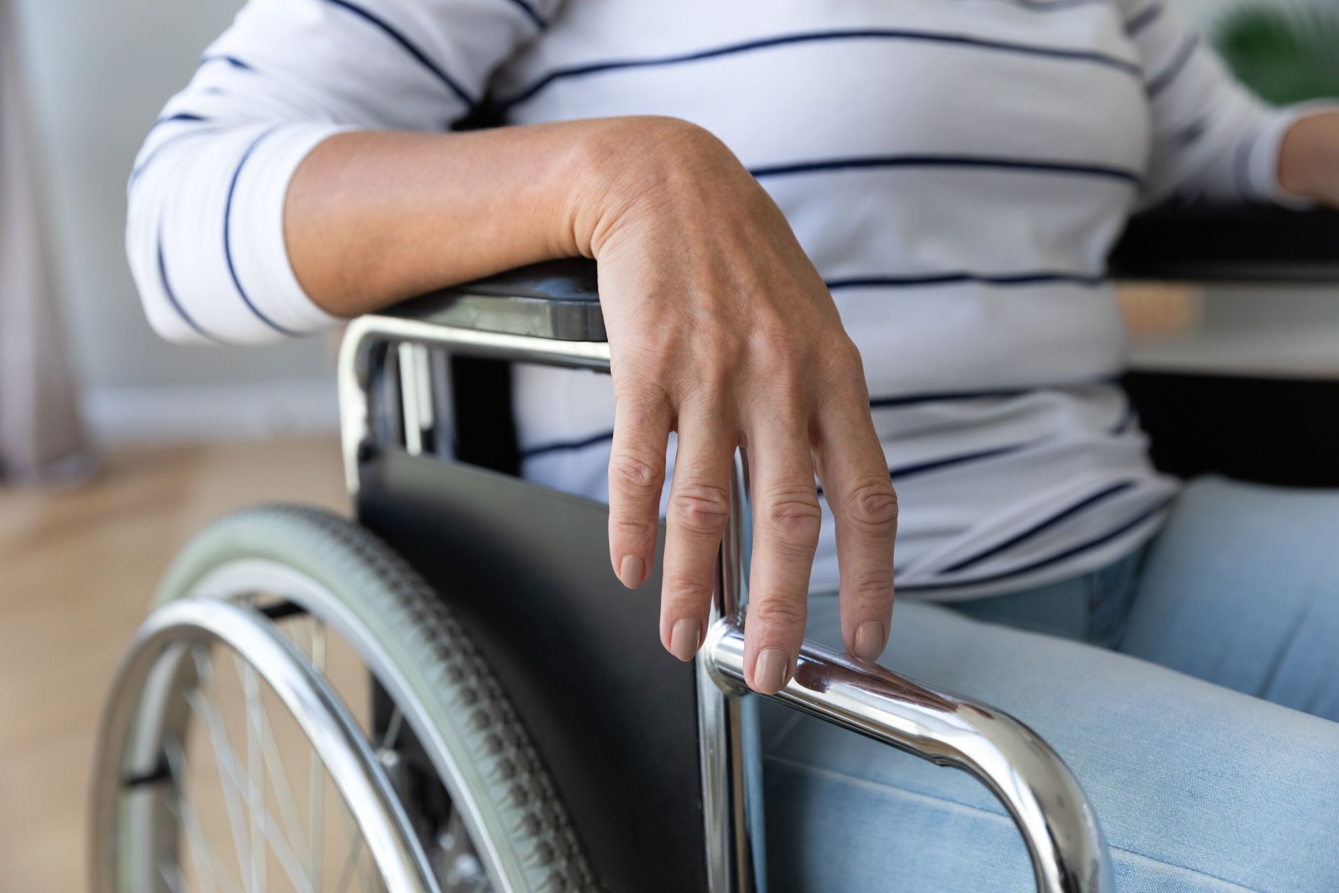 A woman is sitting in a wheelchair with her hand on the handle.