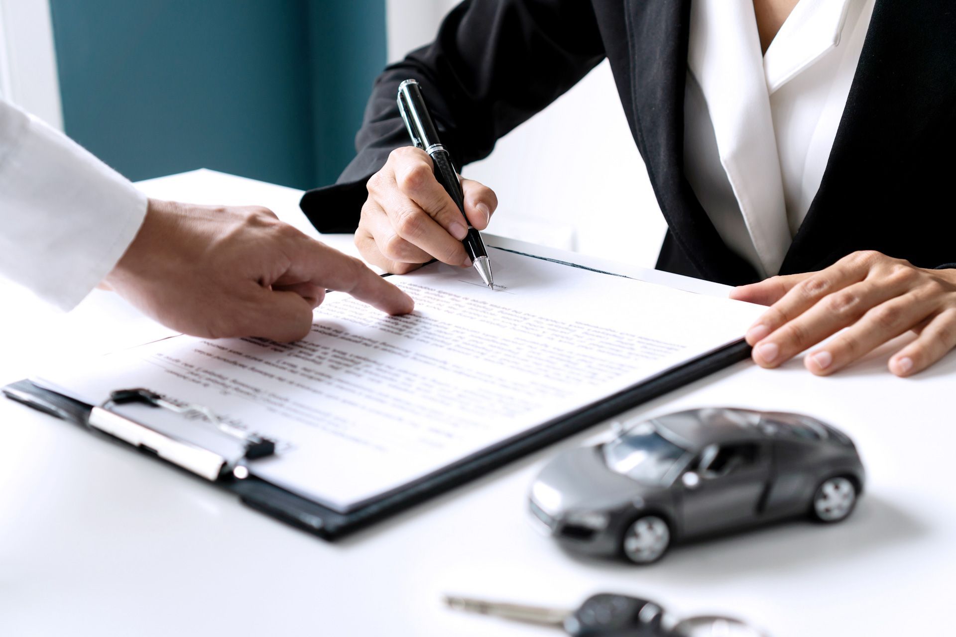 A woman is signing a document next to a toy car.