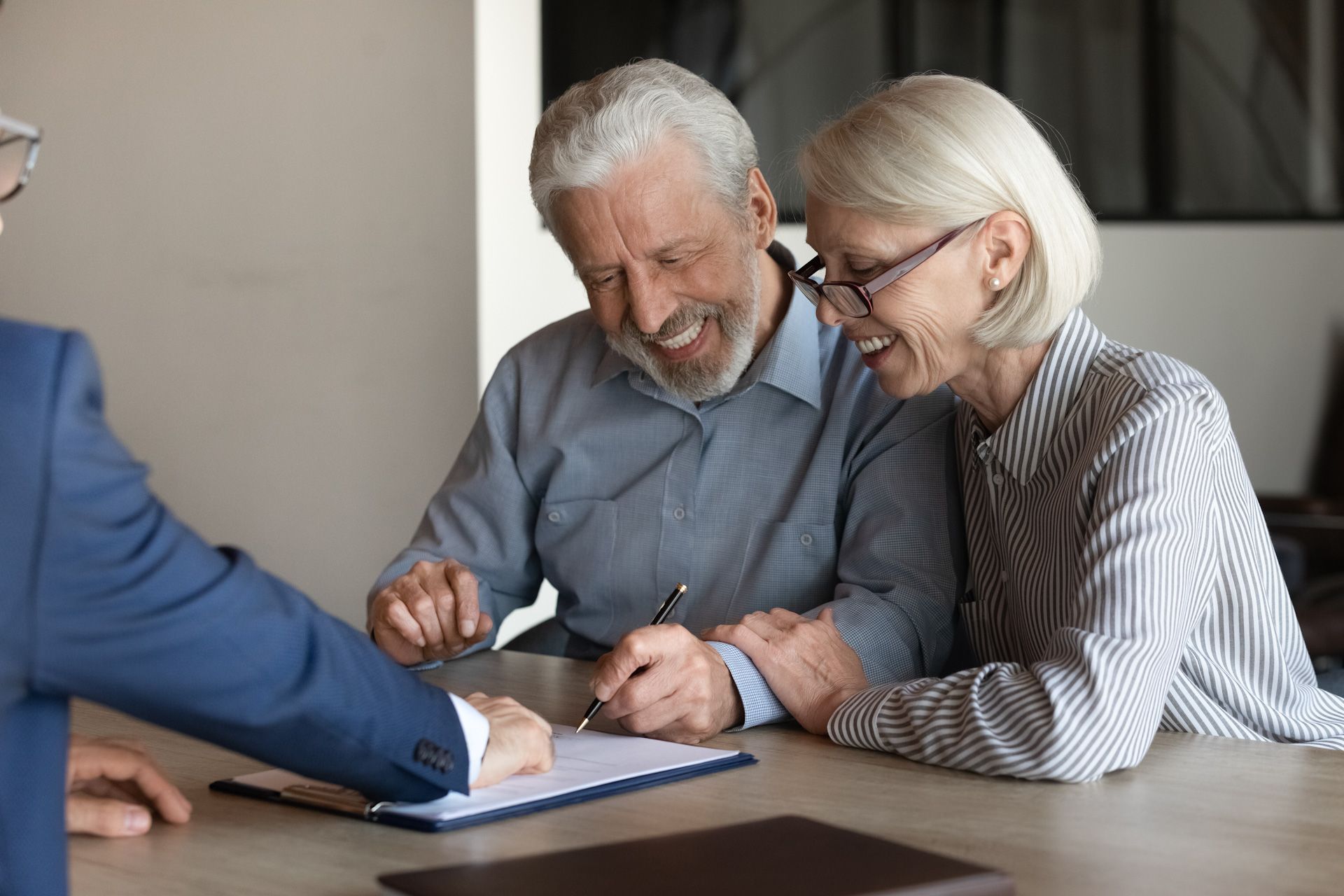 An elderly couple is signing a document with a man.