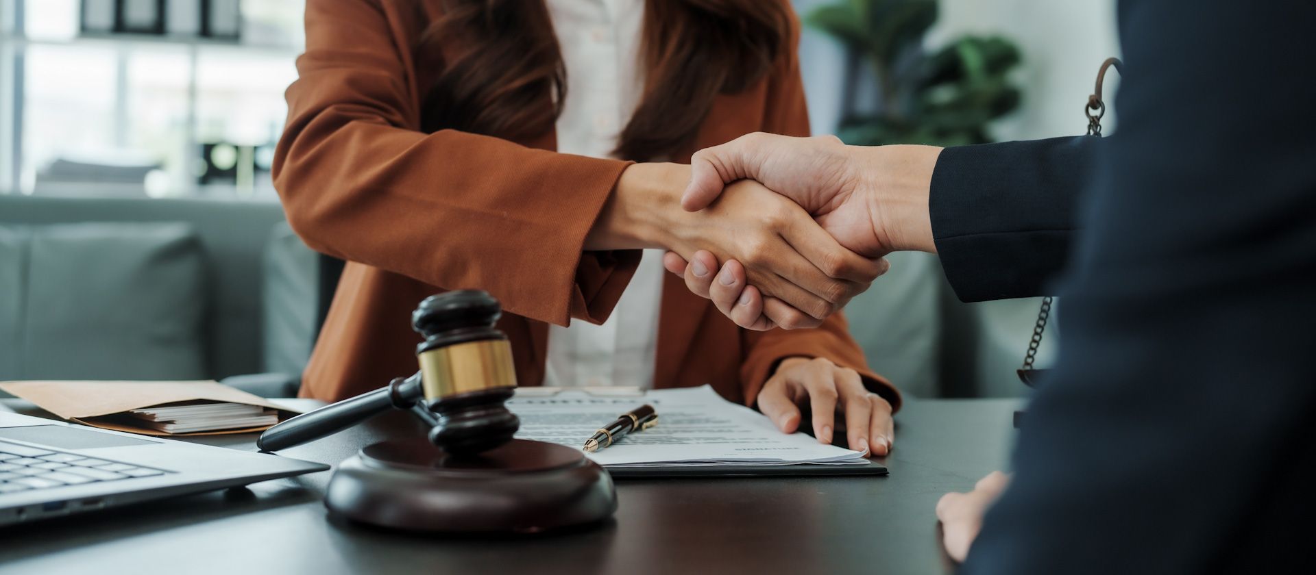 A man and a woman are shaking hands over a table.