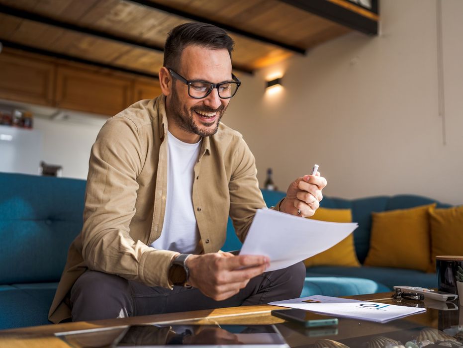 A man is sitting on the floor looking at a piece of paper.