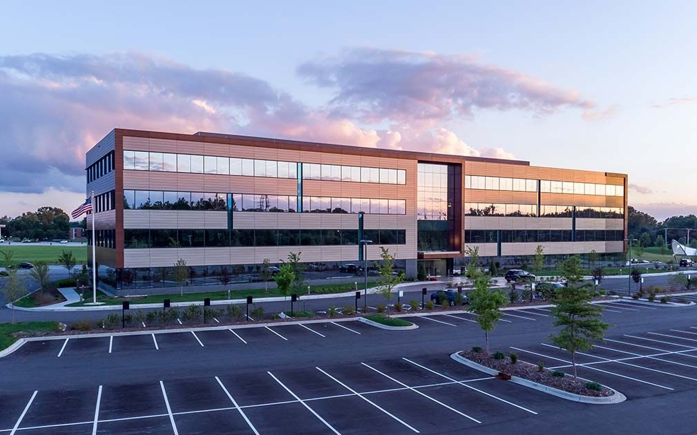 An aerial view of a large office building with a parking lot in front of it.