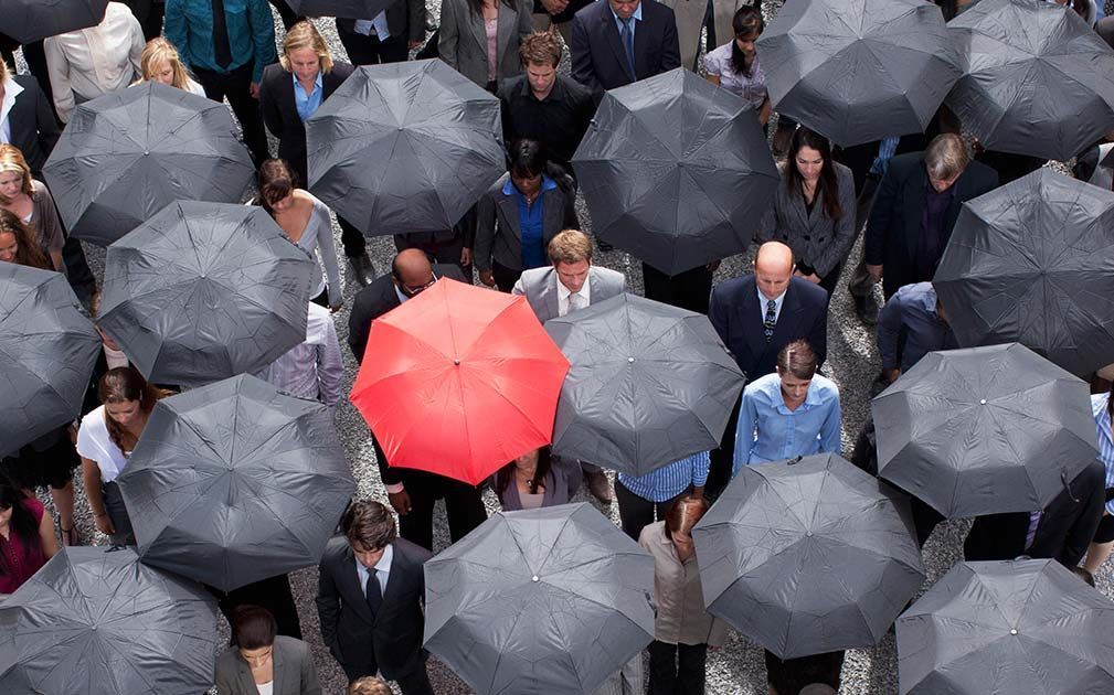 A crowd of people holding umbrellas including a red one