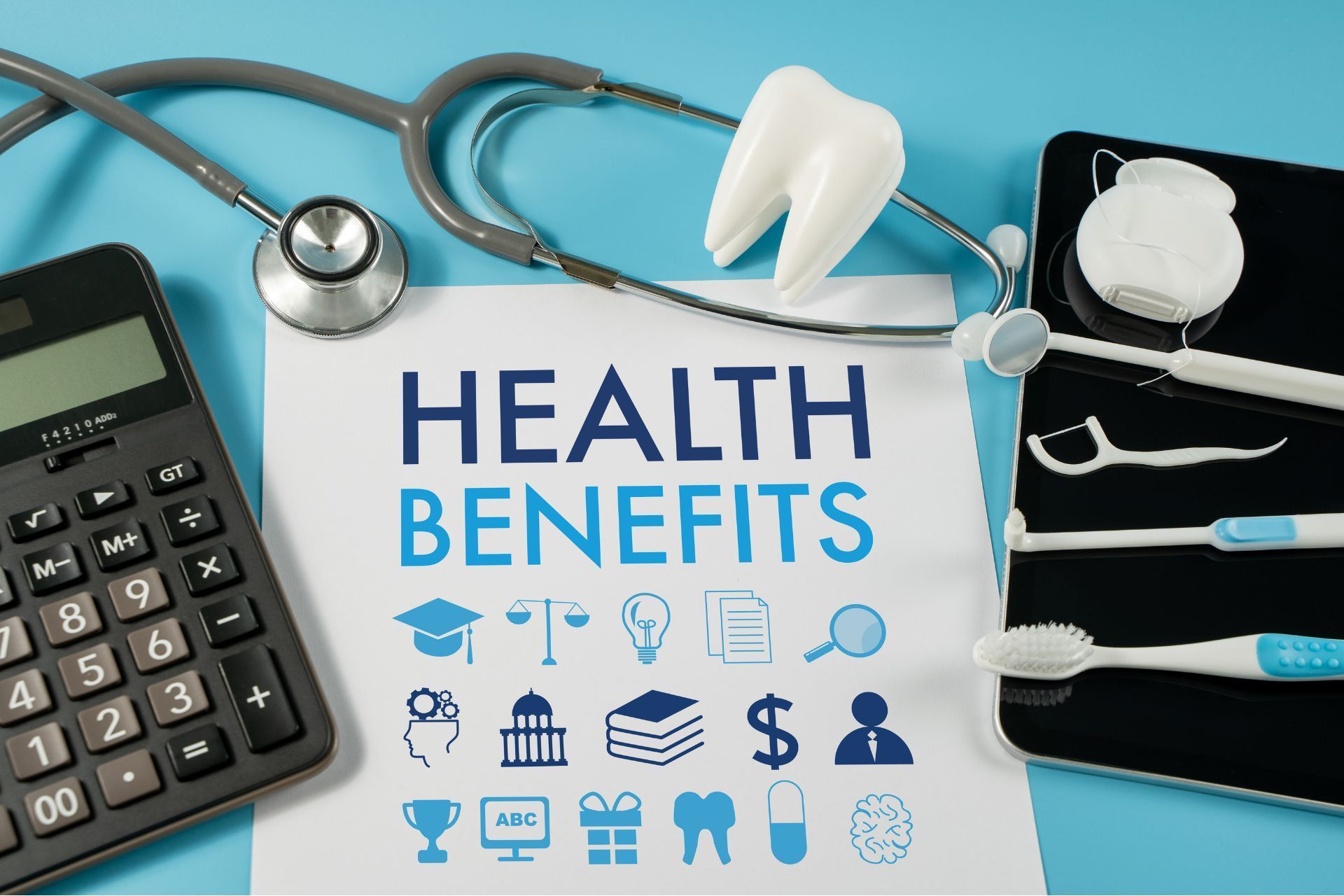 A calculator , toothbrushes , a stethoscope , and a piece of paper that says health benefits.