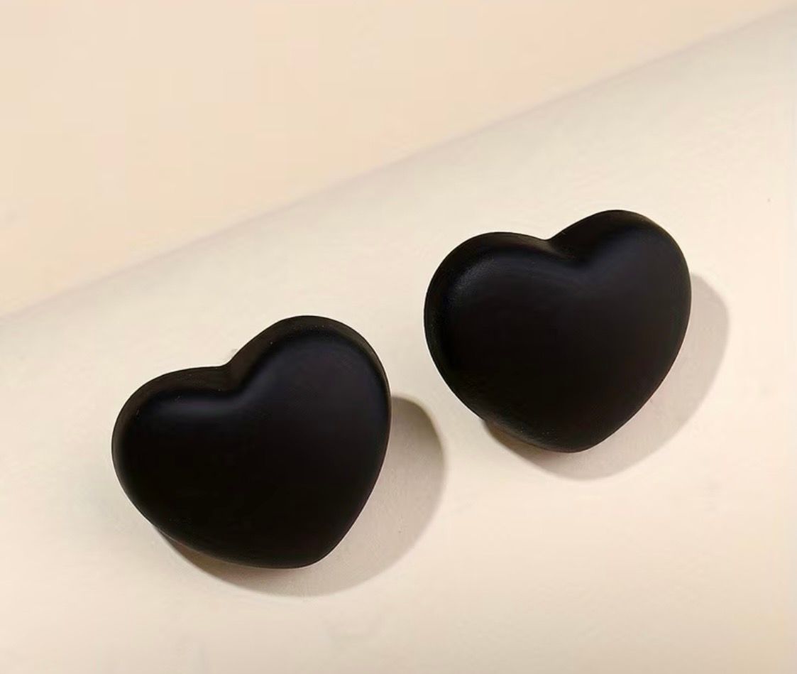 Two black heart-shaped wall hooks on a light-colored wall
