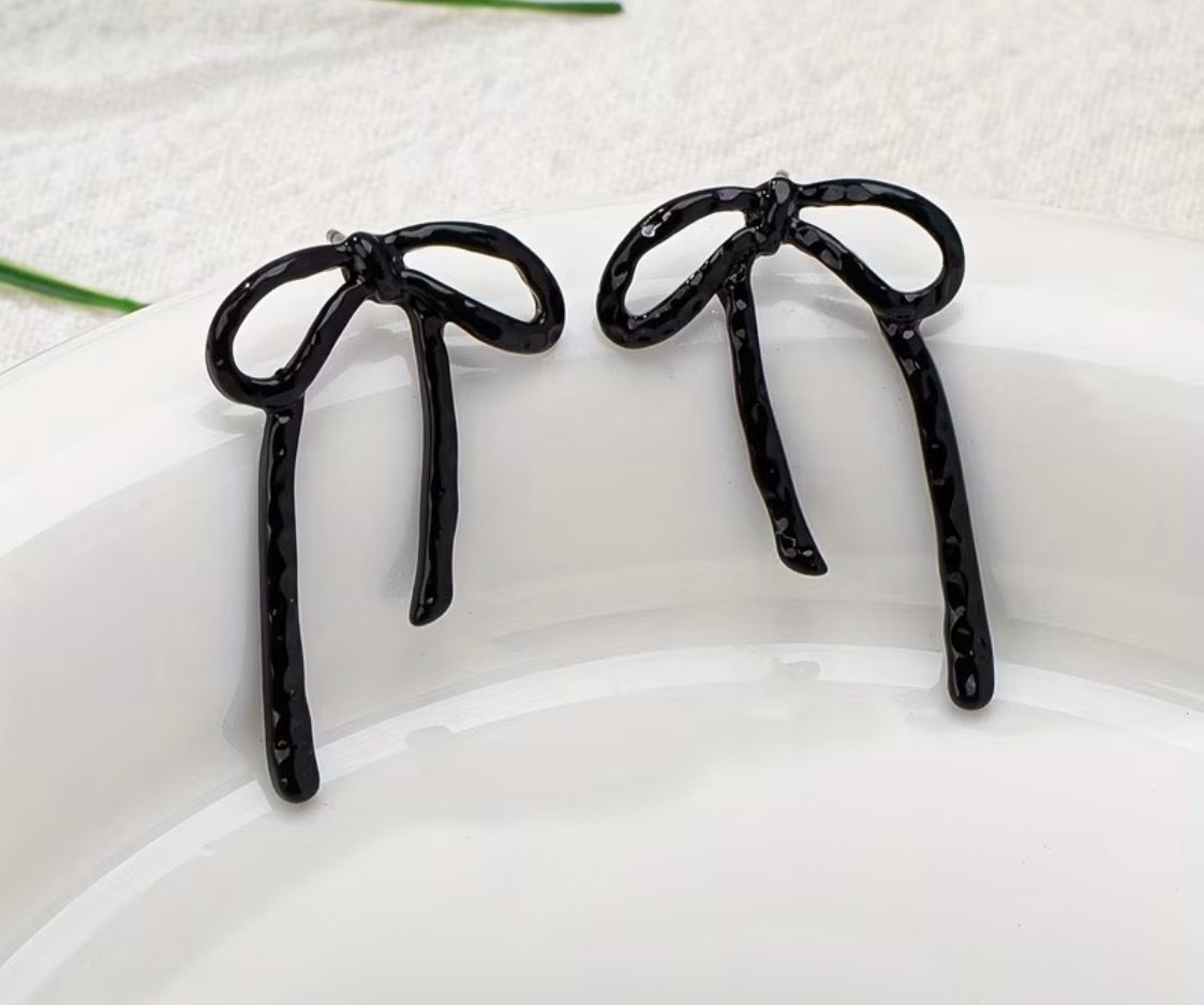 Two black hair ribbons with long tails on a white surface