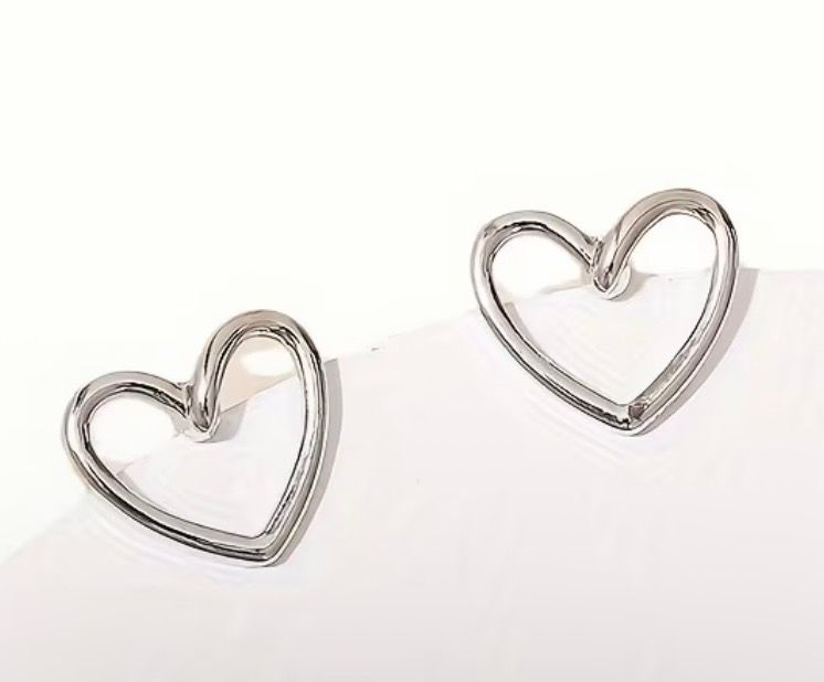 Two silver heart-shaped earrings on a white background
