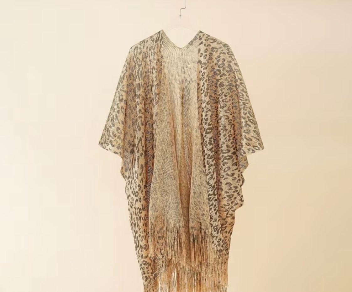 Beige and brown patterned sheer kaftan-style dress hanging against a plain wall