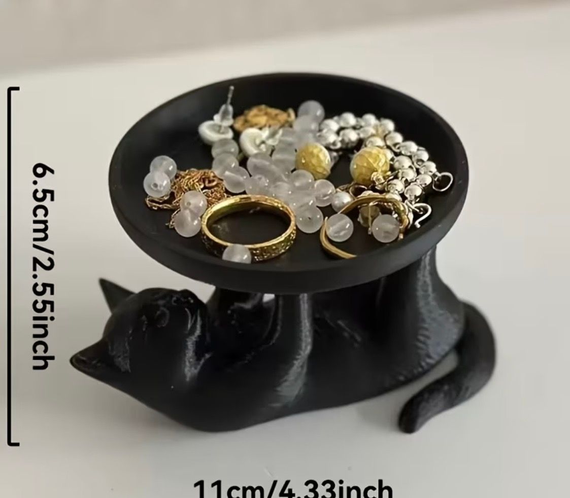 Black cat-shaped ring holder with a dish of assorted rings and beads on top