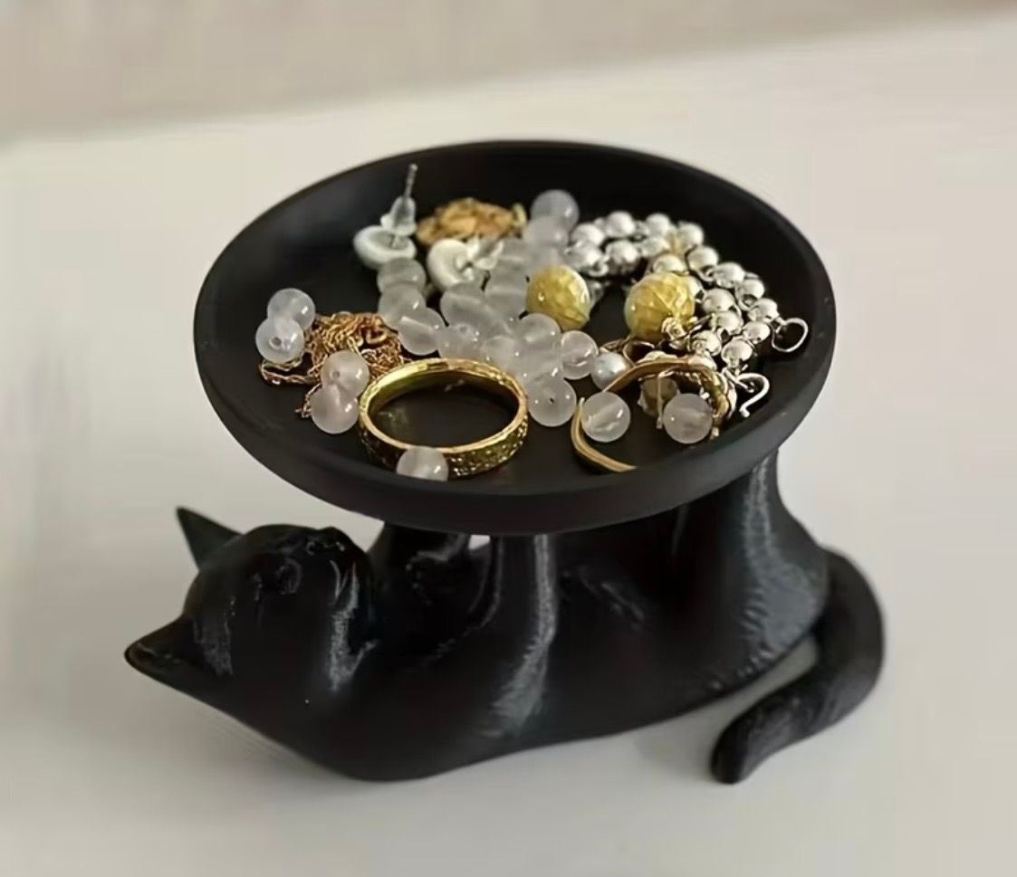 Black cat-shaped ring holder with a dish of assorted rings and beads on top