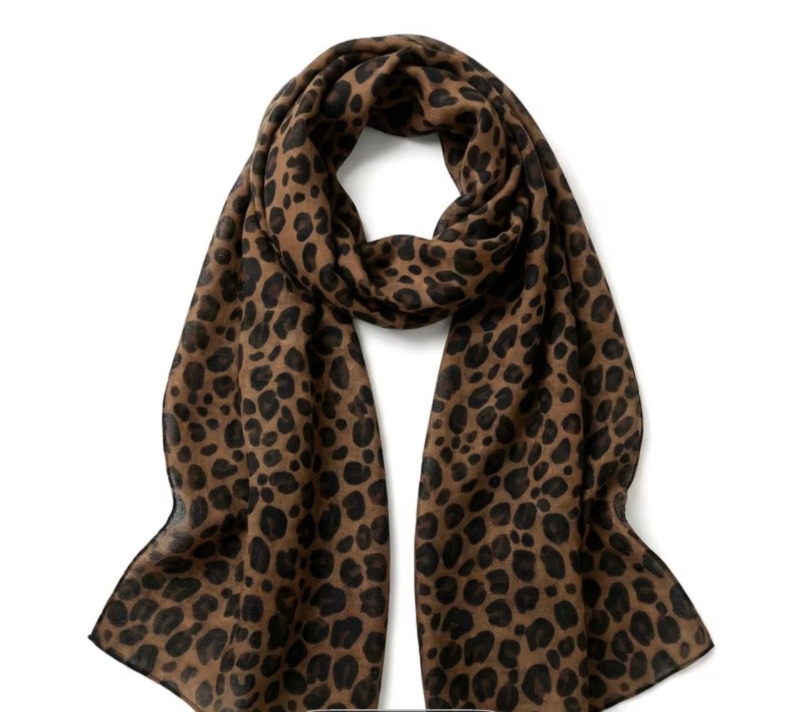 Leopard-print brown scarf with black spots, draped and looped against a white background