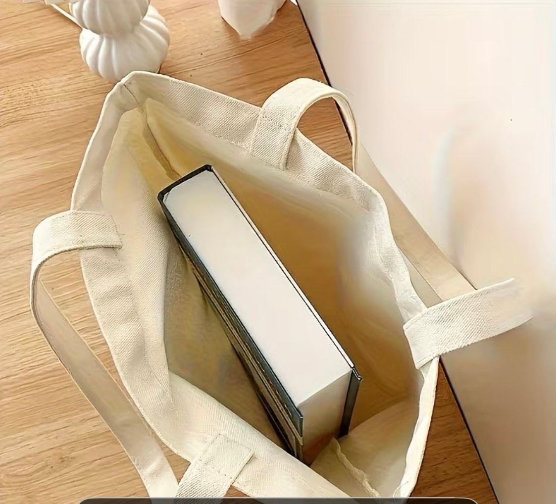 Canvas tote bag reading “Plant Addict Social Club” with potted plant illustrations on a wooden floor