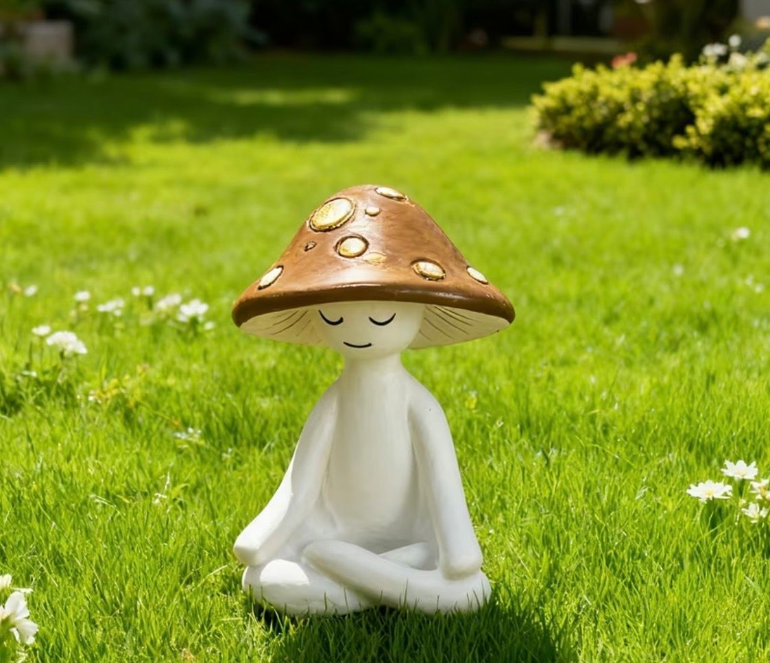 Small white figurine meditating on green grass, wearing a brown mushroom cap hat.