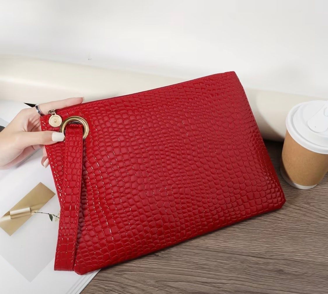 Red textured clutch with gold ring on a table beside a coffee cup and white box