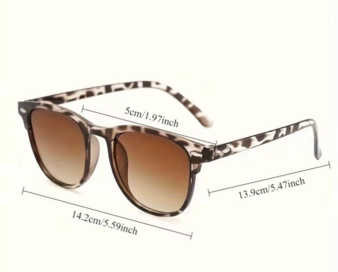 Leopard-print sunglasses with brown lenses on a light surface in soft sunlight