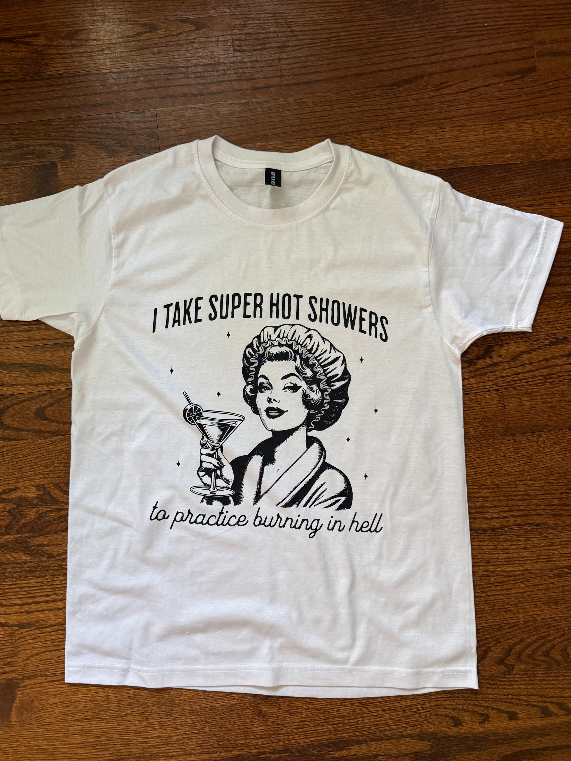 White T-shirt with a black graphic and text reading “I TAKE SUPER HOT SHOWERS.”
