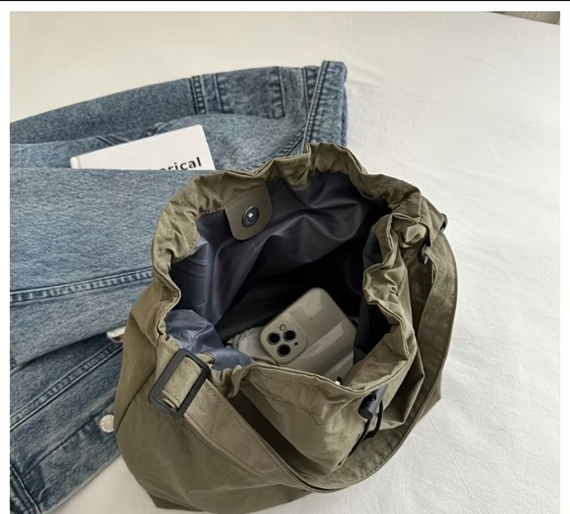 Beige drawstring tote bag on a table beside a white box and window blinds