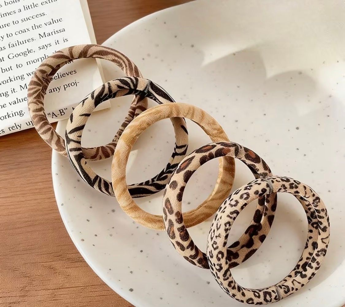Leopard-print scrunchies piled on a cardboard box on a wooden surface