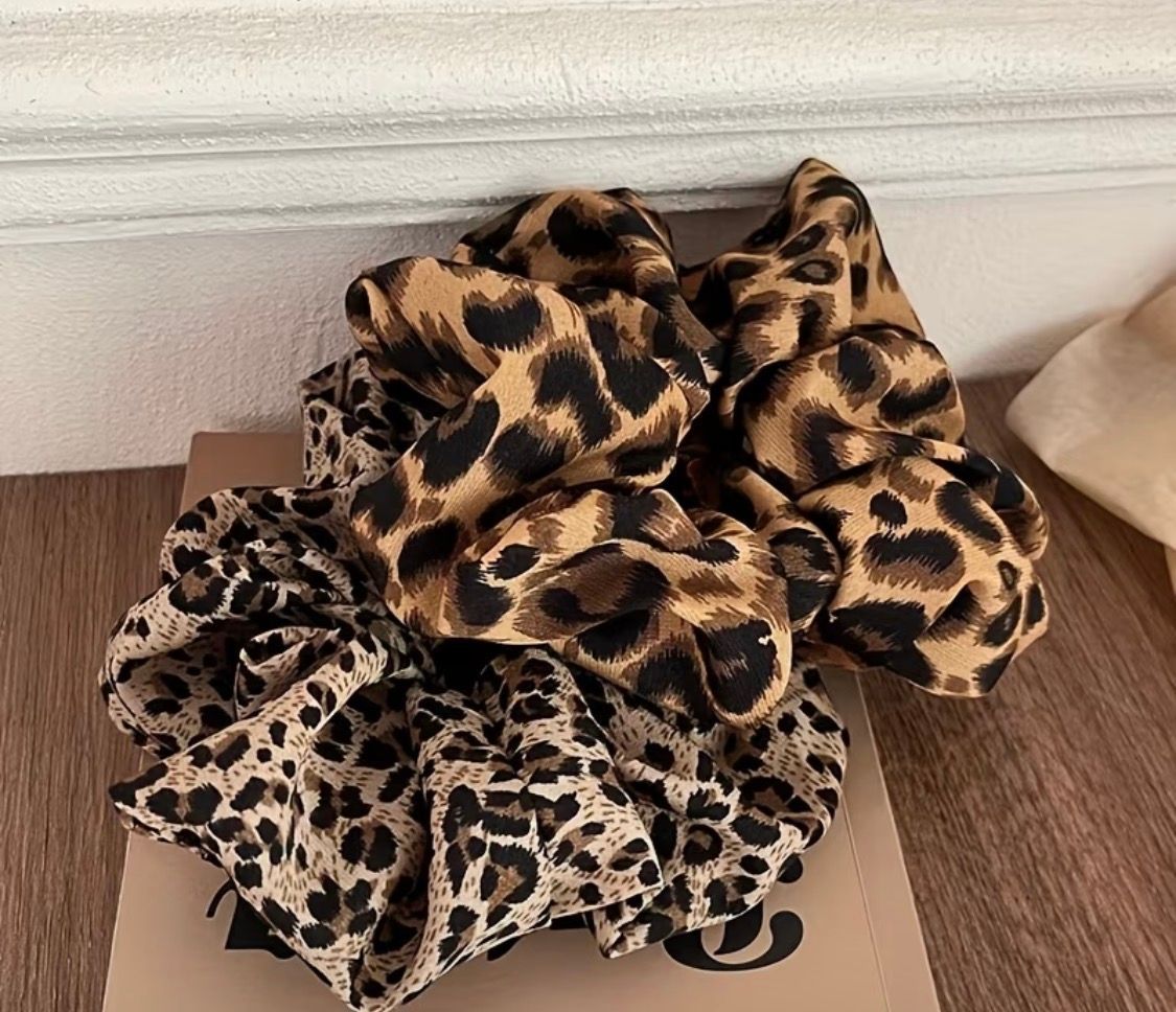 Leopard-print scrunchies piled on a cardboard box on a wooden surface