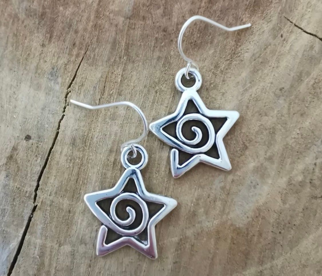 Pair of silver spiral star dangle earrings on a wooden surface