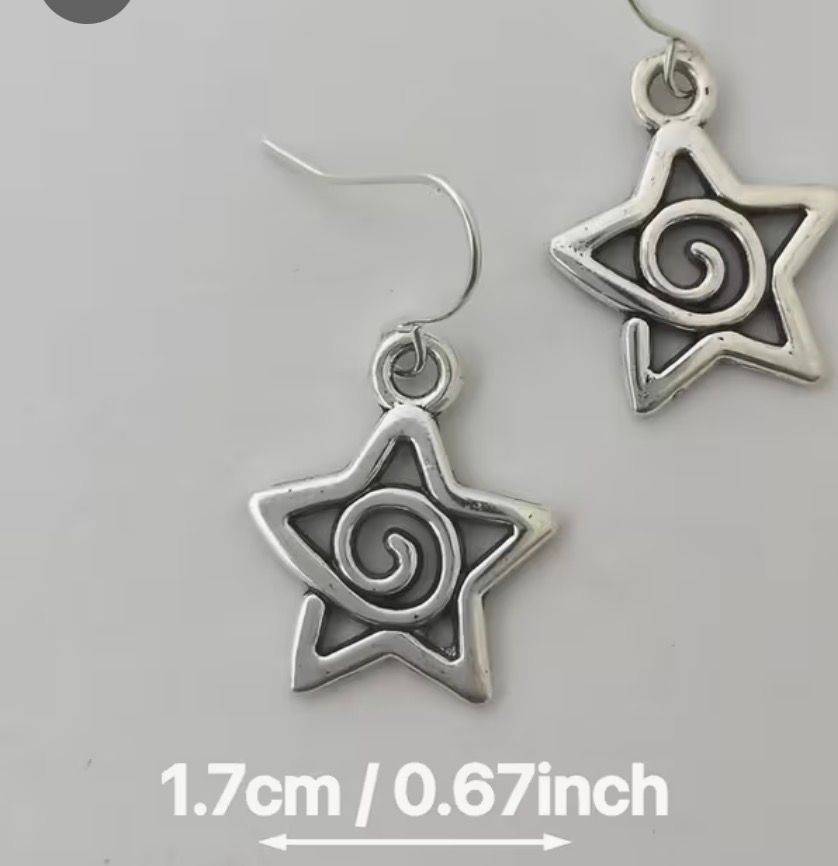 Pair of silver spiral star dangle earrings on a wooden surface