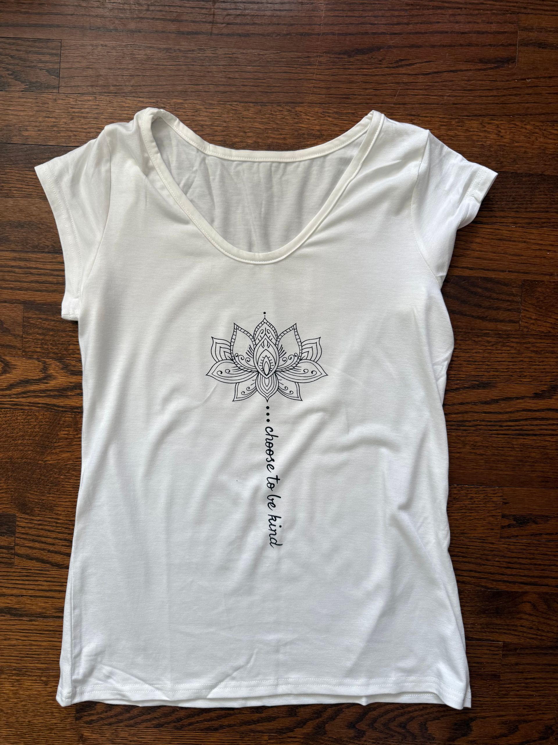 White V-neck T-shirt with a dotted dandelion design on a wooden surface