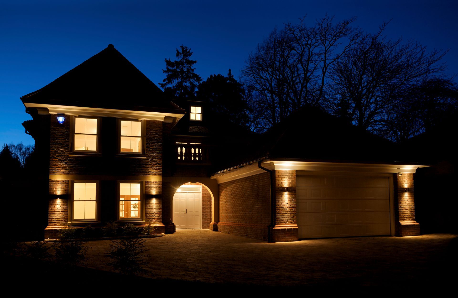 A house with a garage is lit up at night