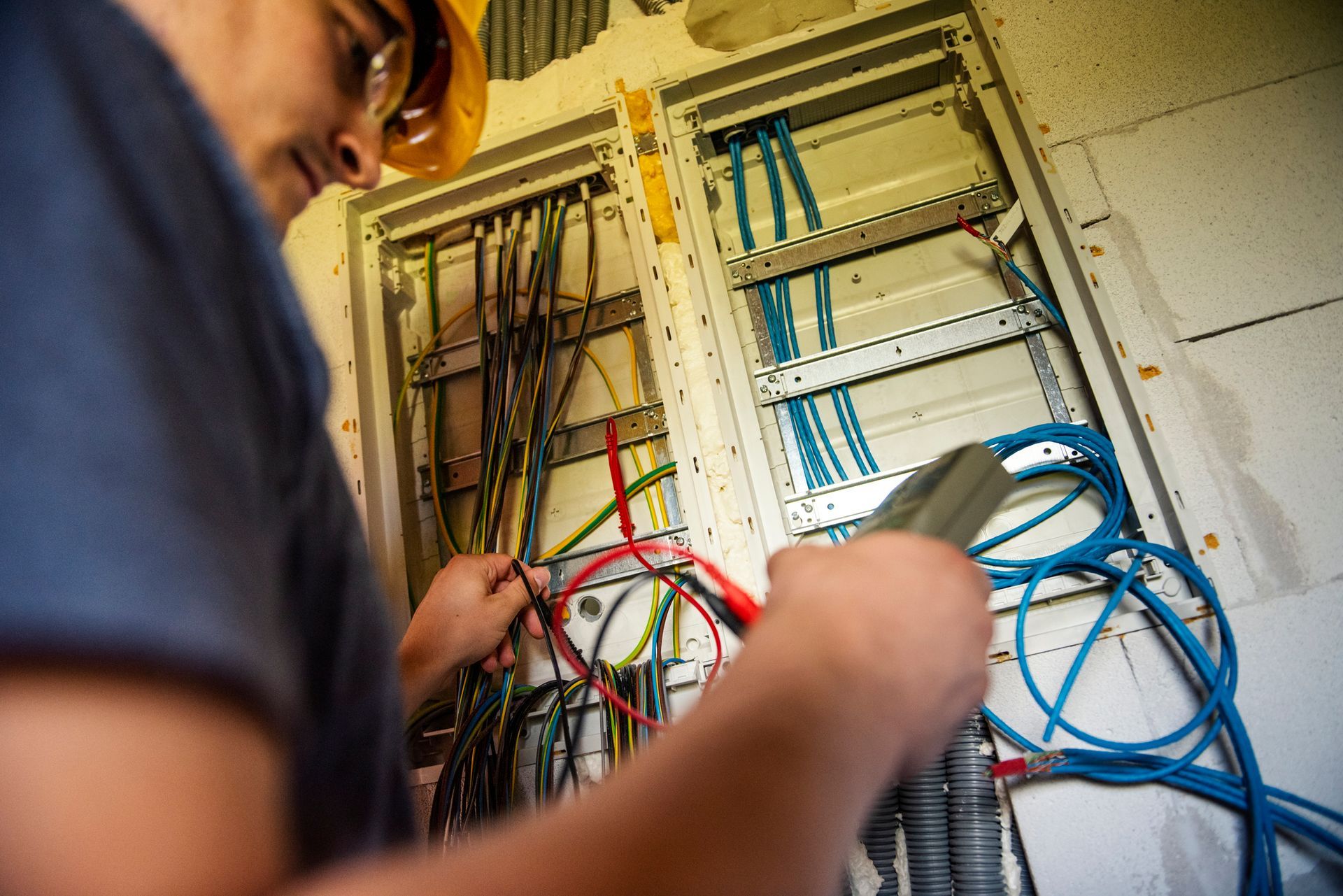 A man is working on an electrical box with a flashlight.