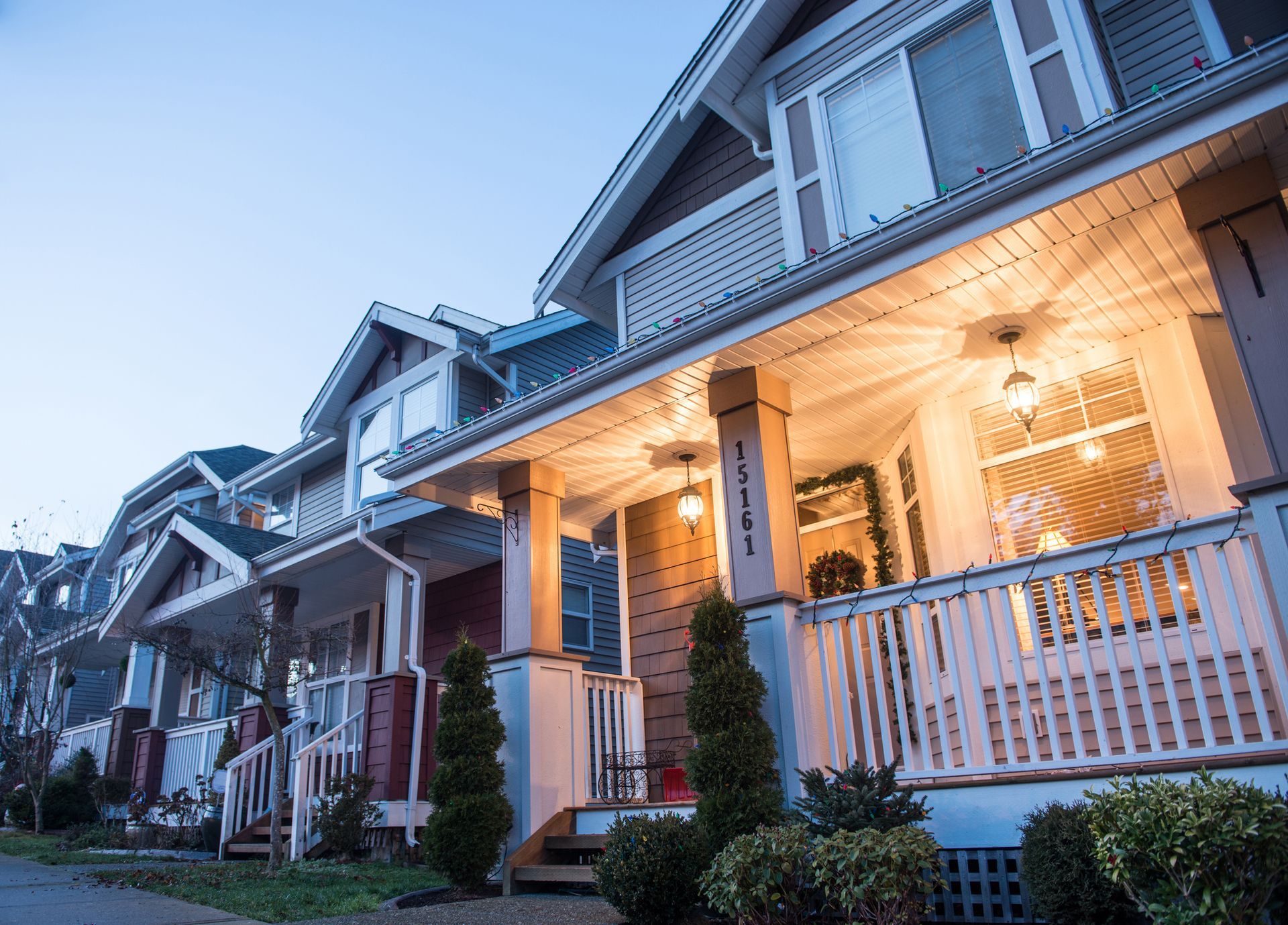 A row of houses with porches are lit up at night.