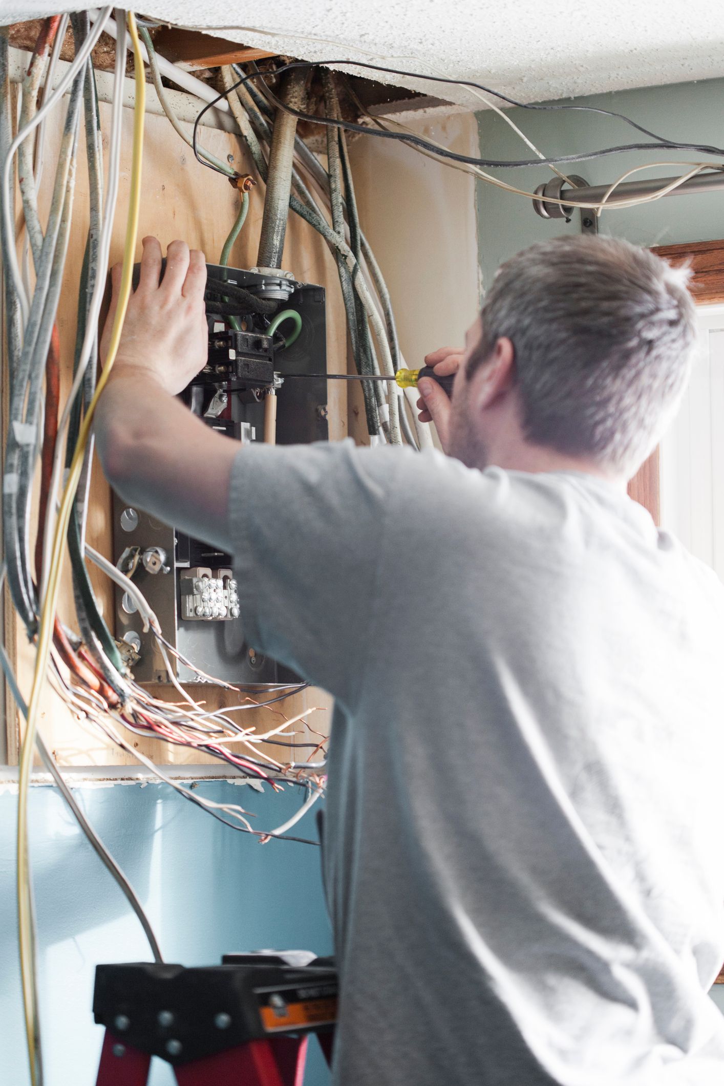 A man is working on an electrical box in a room