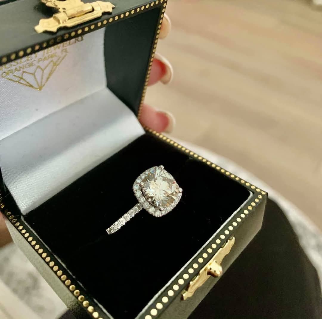 A woman is holding a black box with a diamond ring in it