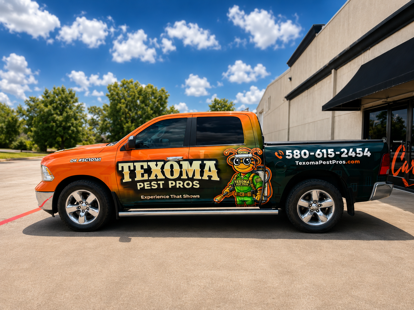 Black and orange pest control truck parked outside a building under a blue sky