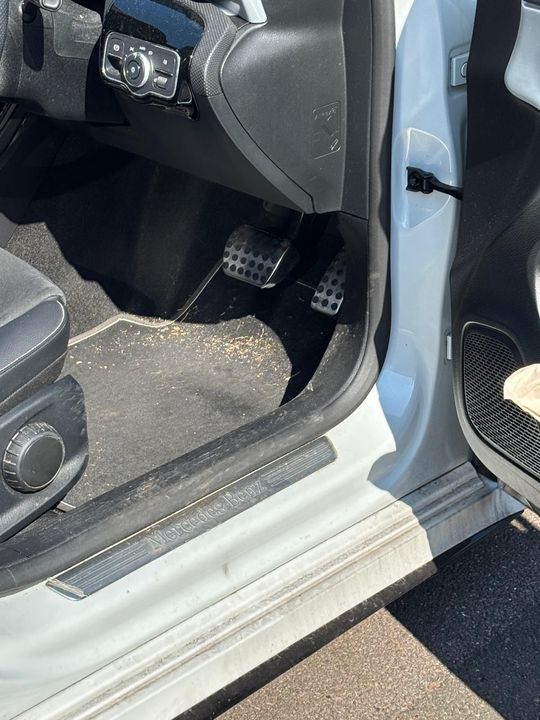 A silver range rover sport is parked in a driveway next to a white van.