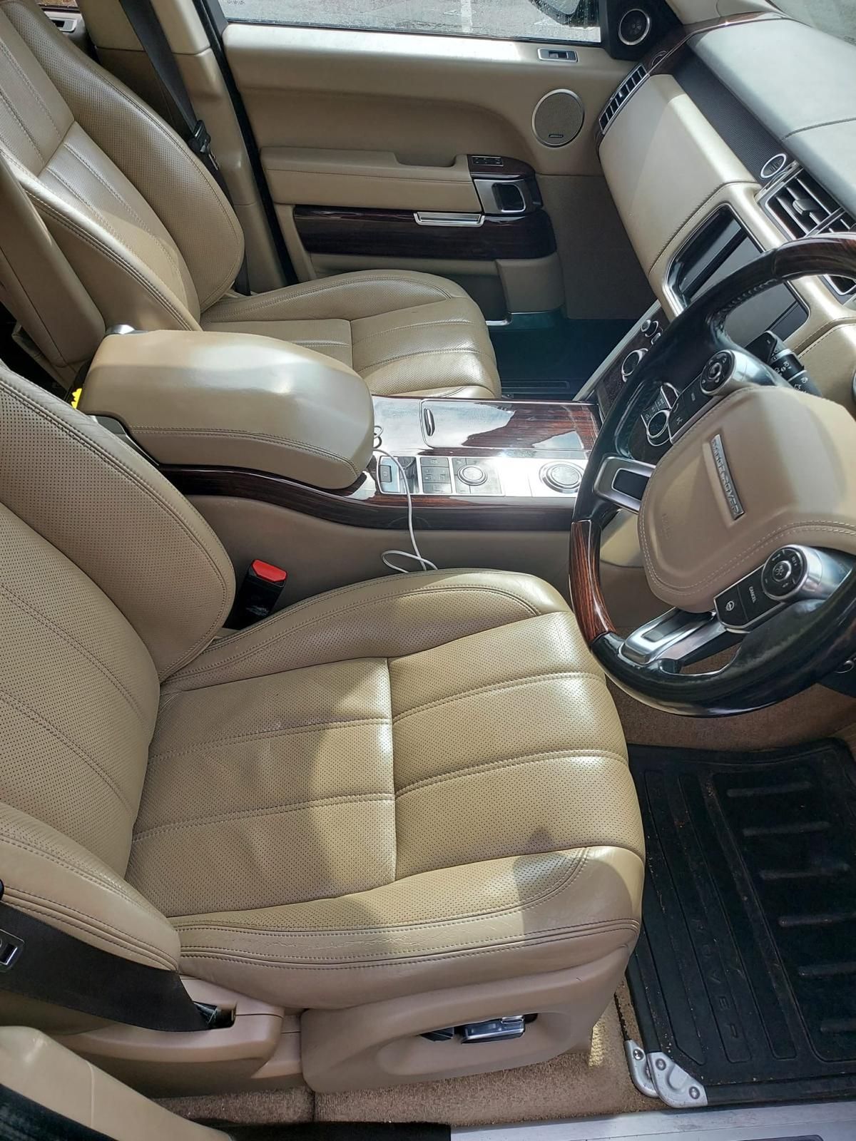 A silver range rover sport is parked in a driveway next to a white van.