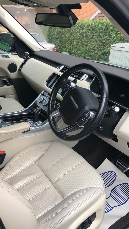 The interior of a range rover sport with white leather seats and a steering wheel has been detailed.