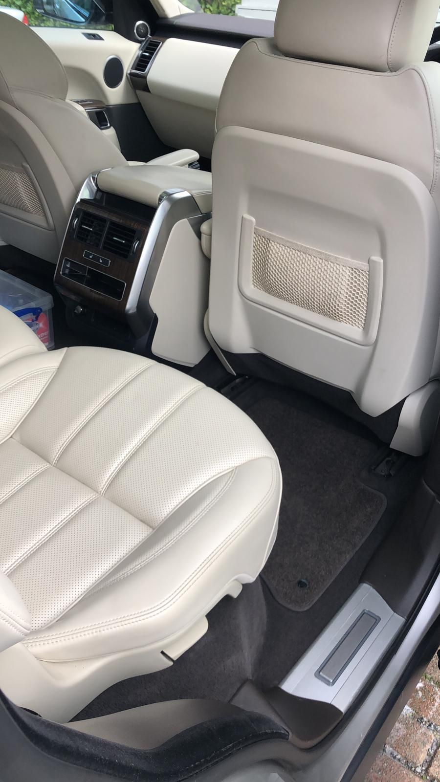 The interior of a range rover sport with white leather seats.