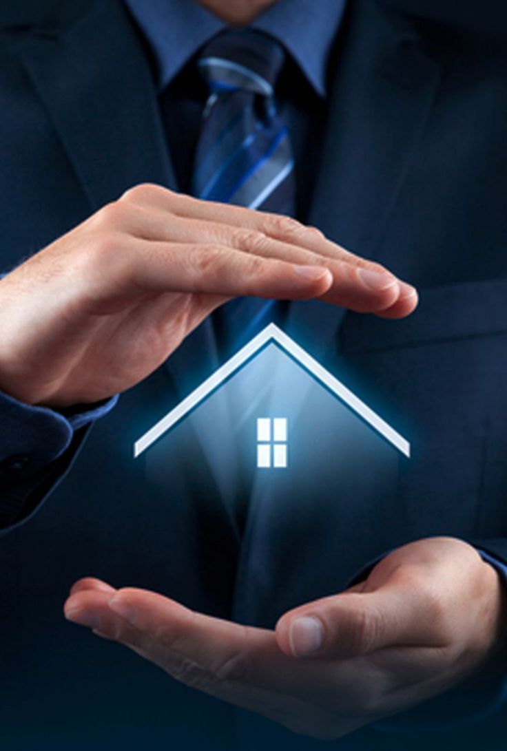 Person in a suit cupping a glowing house graphic in their hands, representing protection and security.