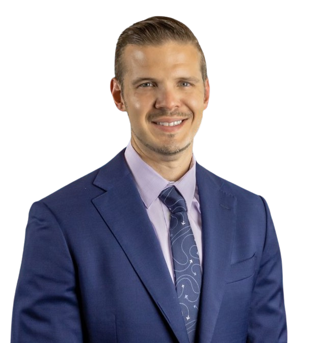 Man in a blue suit and patterned tie smiling, against a white background.