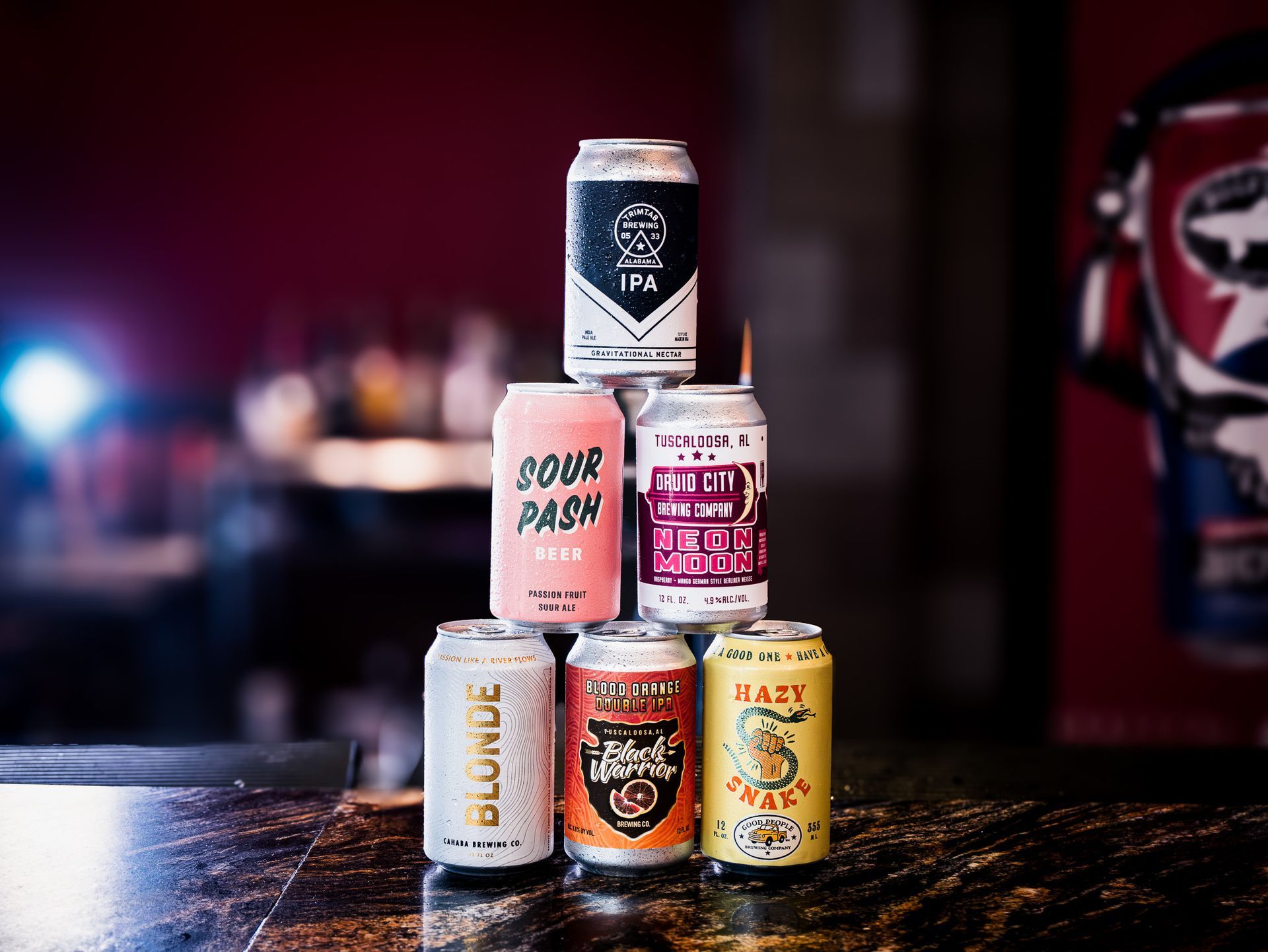 A bunch of cans of beer are stacked on top of each other on a table.