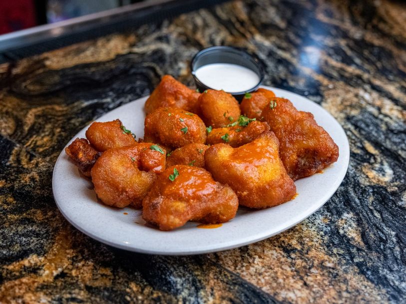A plate of chicken wings with ranch dressing on a table.