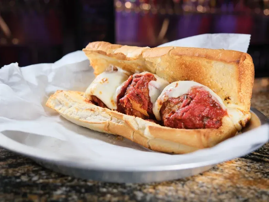 Meatball sub sandwich on a metal plate, with melted cheese, in a soft white bread.