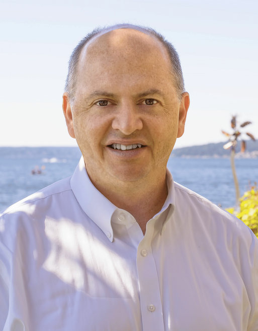 A woman is sitting at a desk with a laptop and a vase of flowers.