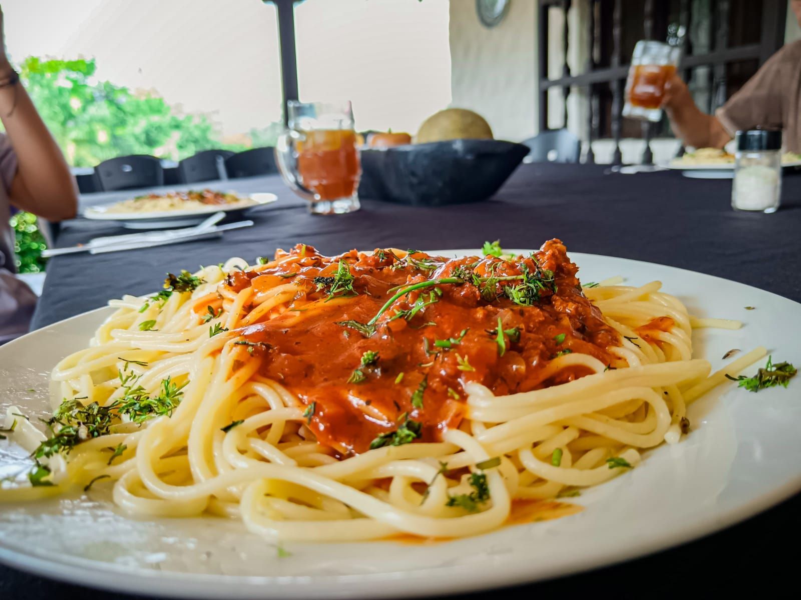 Un hombre con uniforme azul repara un aire acondicionado montado en una pared blanca. Usa un destornillador.