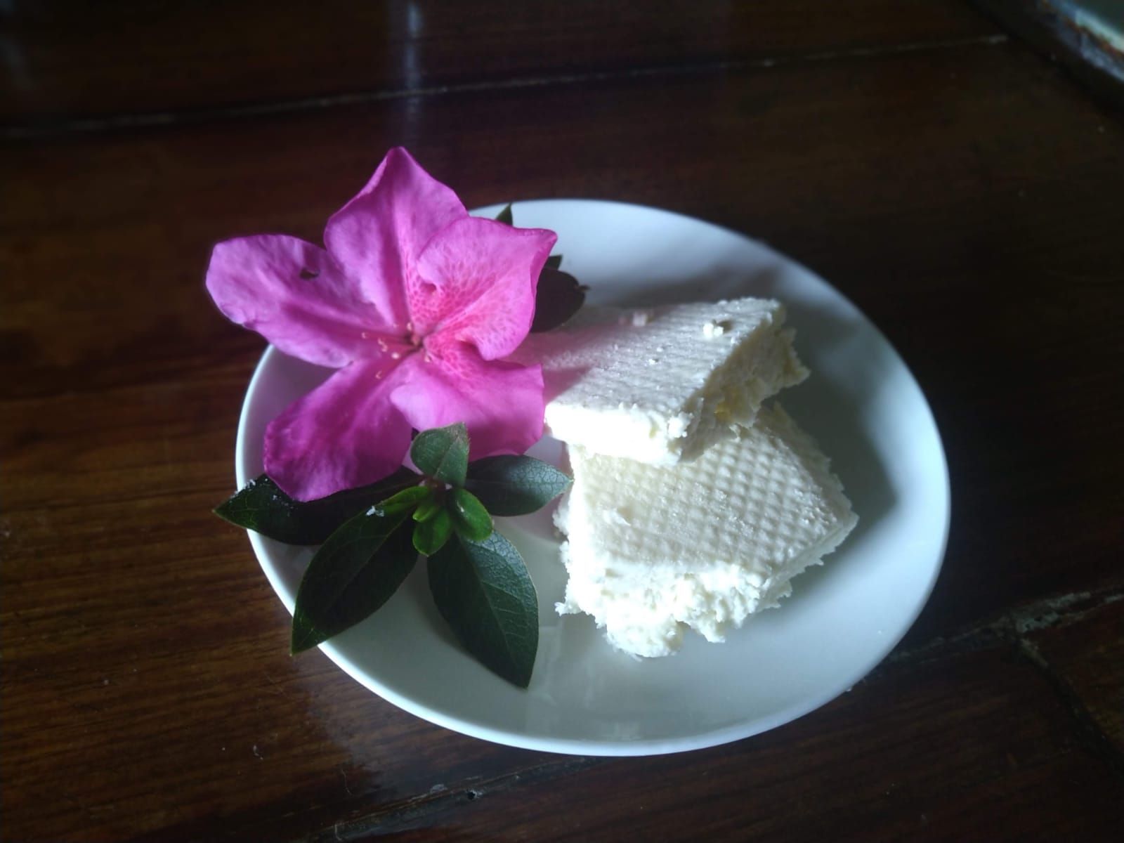 Césped verde con piscina, árboles, cenador y vistas a la montaña.