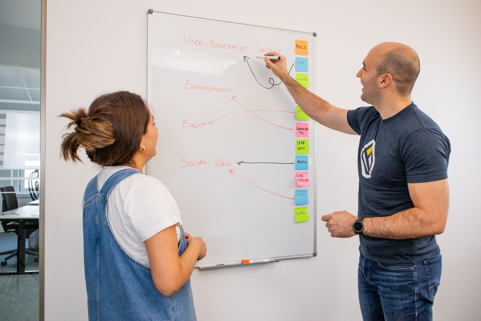 Small marketing team collaborating around a table with a laptop and printed charts in a bright office