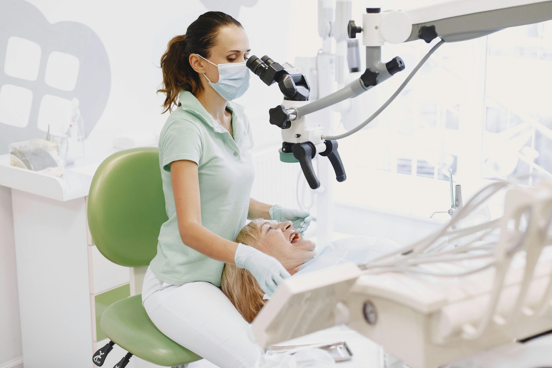 Dental clinician examining a patient with a microscope in a bright dental office