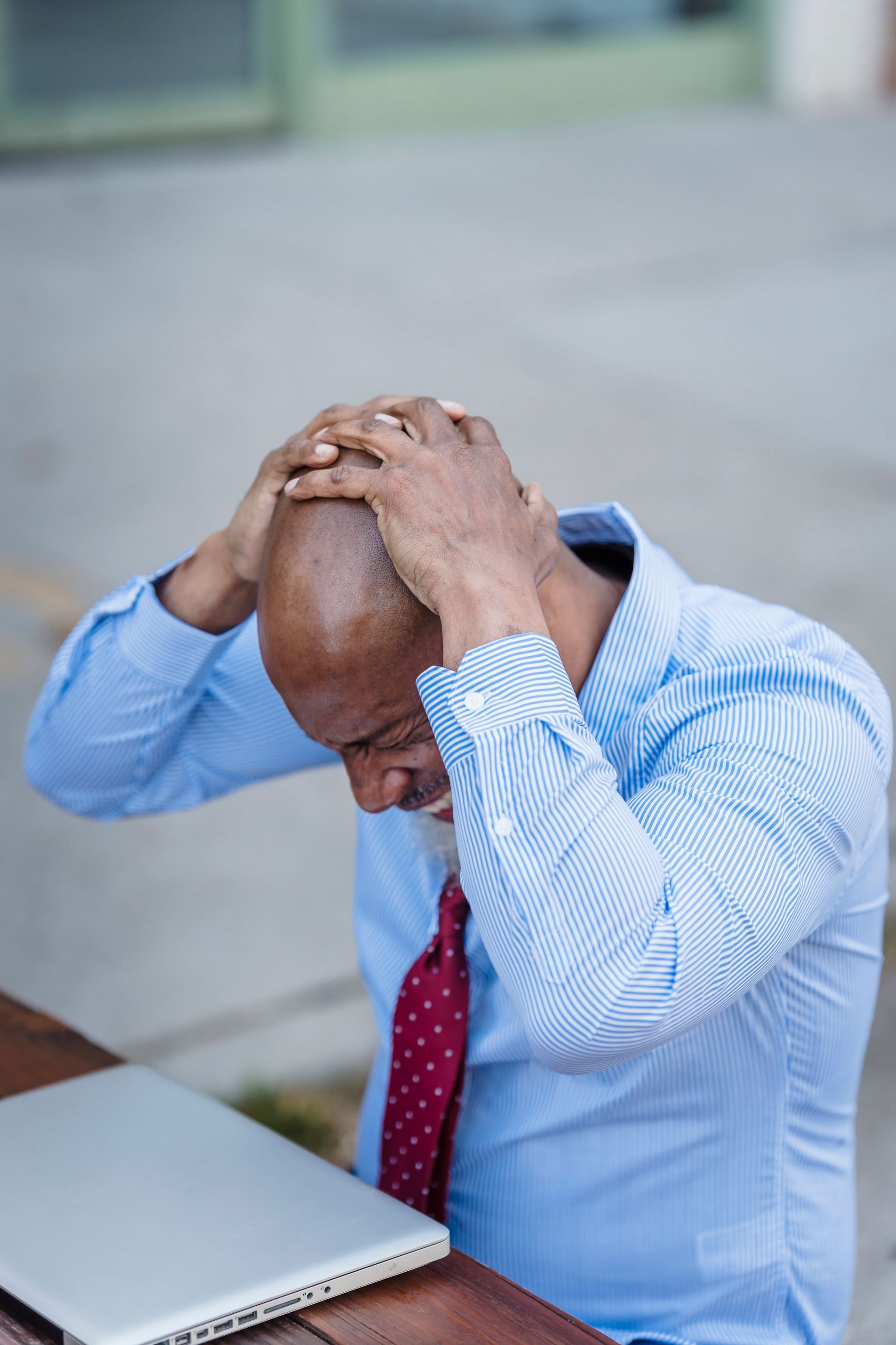 Small business owner looking thoughtfully at a laptop at a desk in a bright office